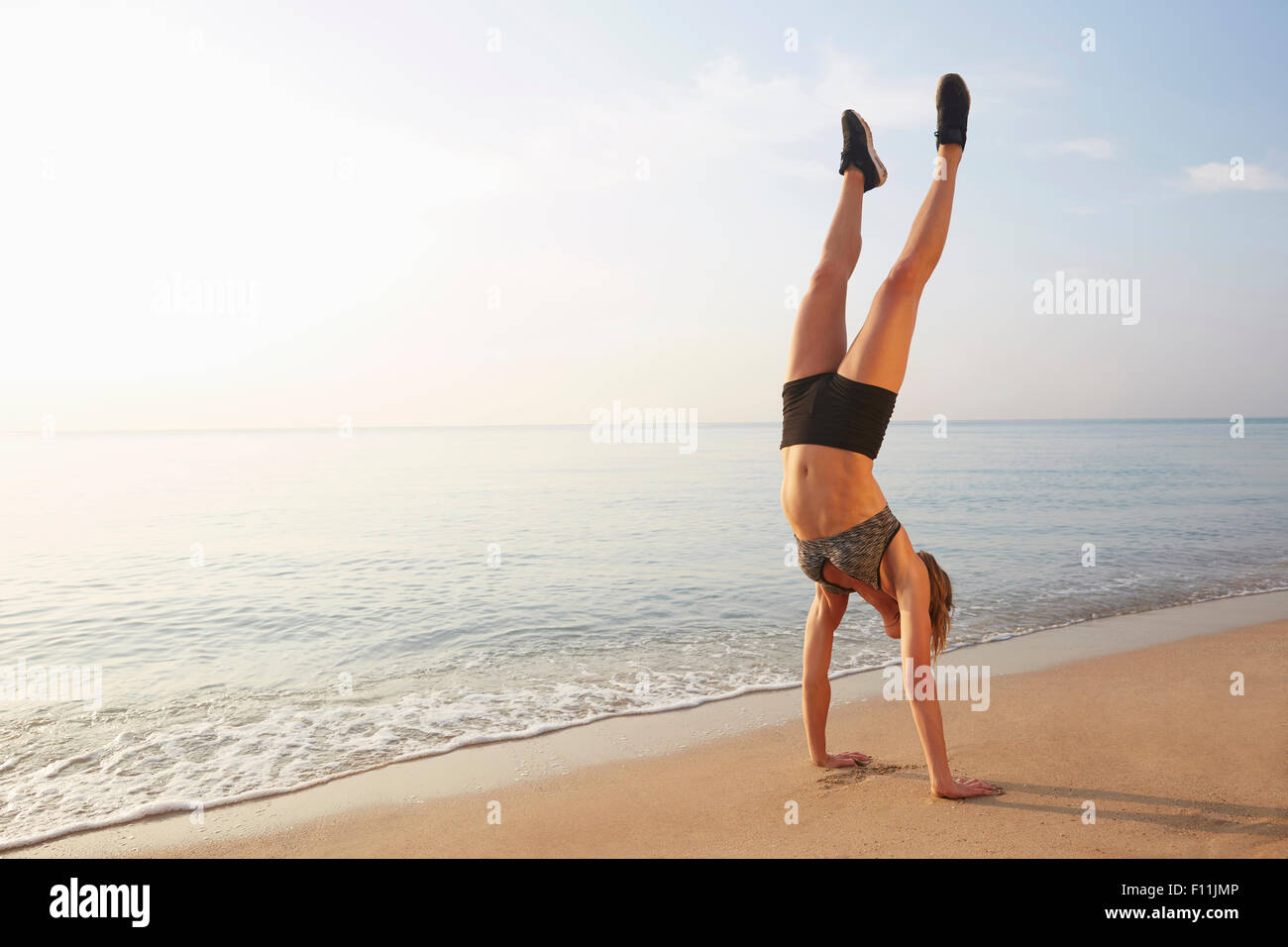 Athlete doing handstand on beach Stock Photo
