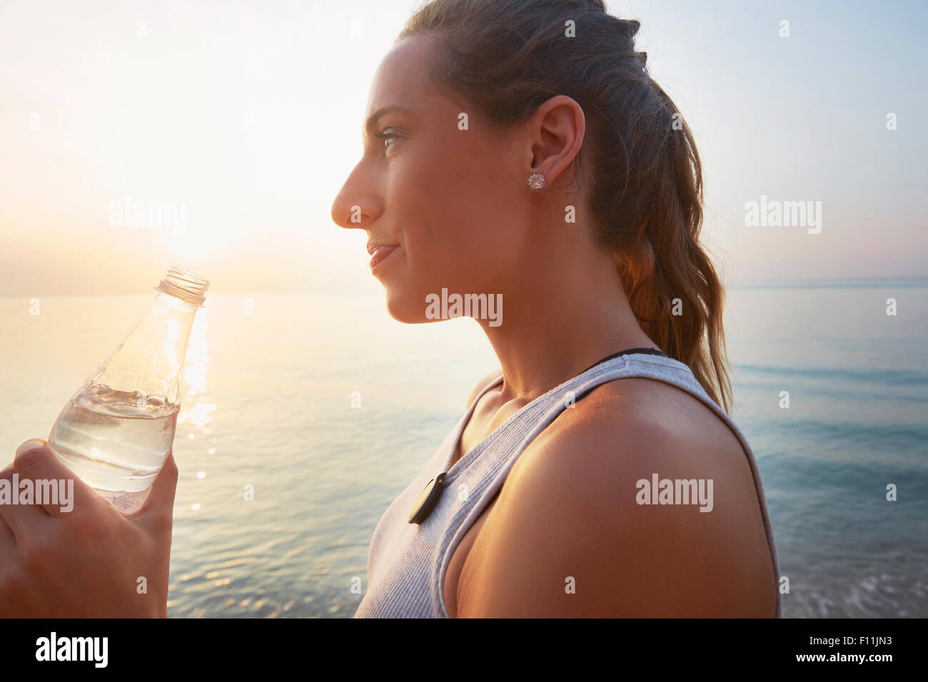 Athlete drinking water bottle on beach Stock Photo