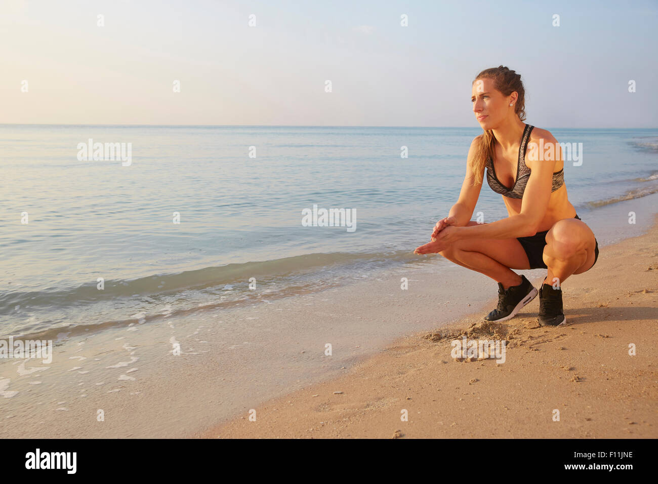 Athlete crouching on beach Stock Photo