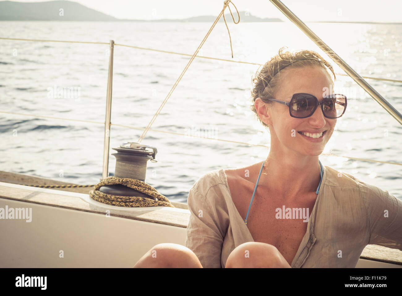 Smiling Caucasian woman sitting on boat deck Stock Photo