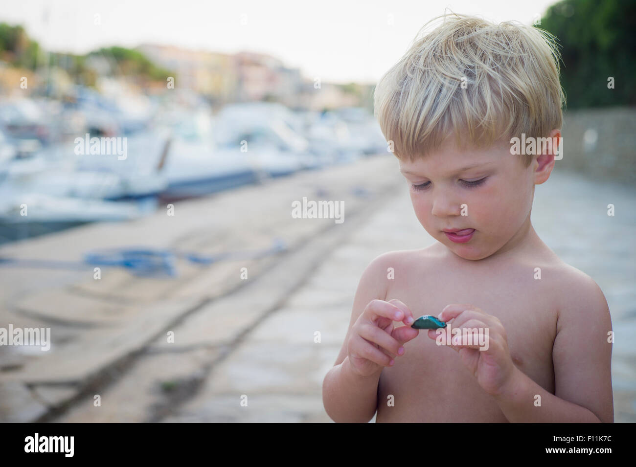 Curious Caucasian boy playing with rock Stock Photo