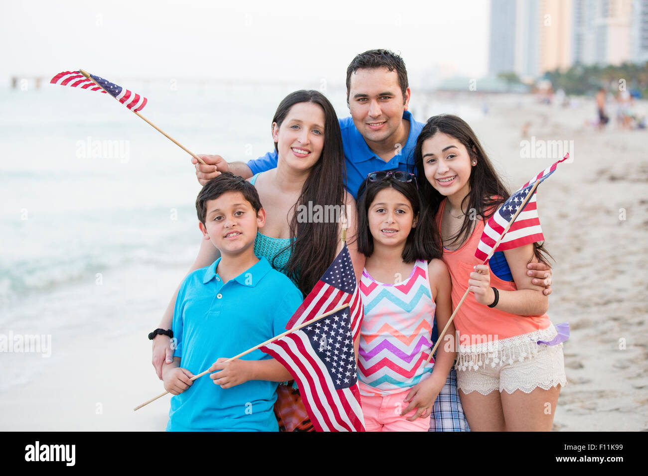 Hispanic family waving American flags on beach Stock Photo