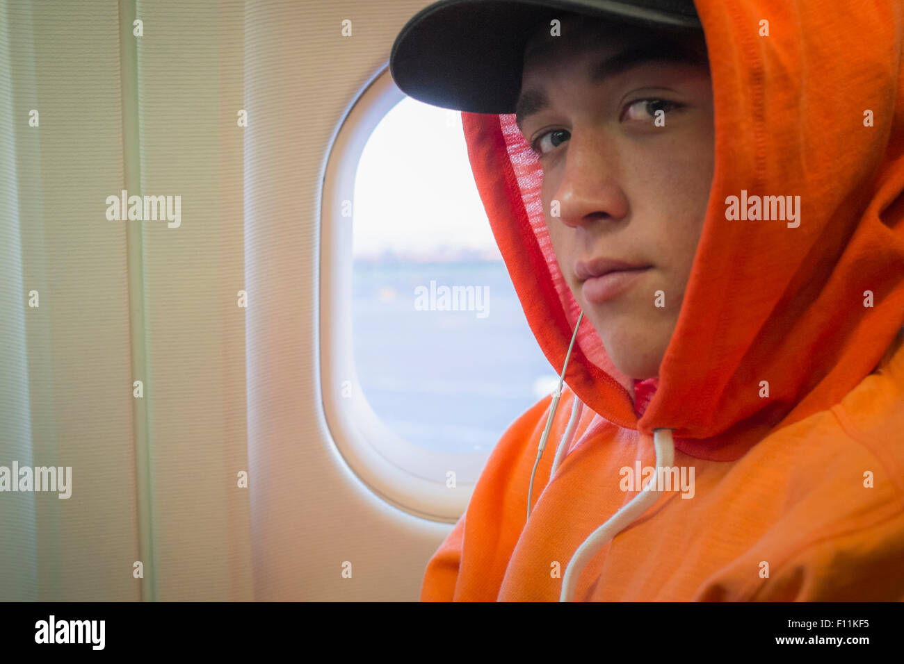 Caucasian man wearing hoodie on airplane Stock Photo