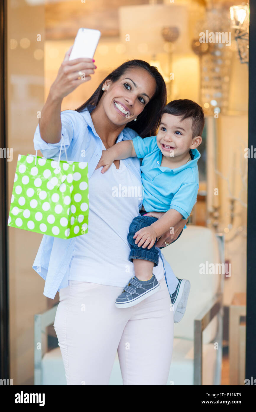 Hispanic mother and son taking selfies and shopping Stock Photo