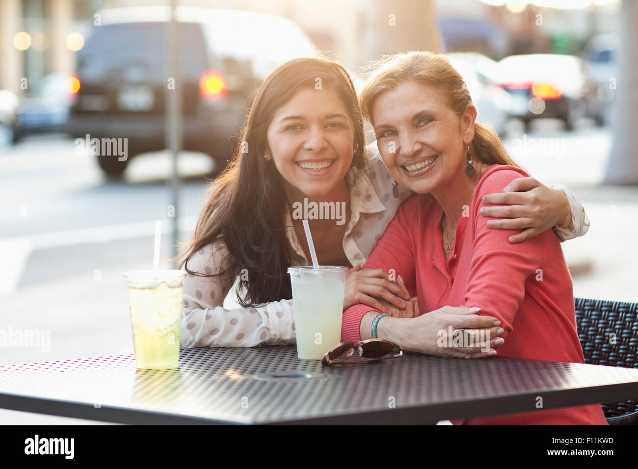 Mother and daughter hugging at sidewalk cafe Stock Photo