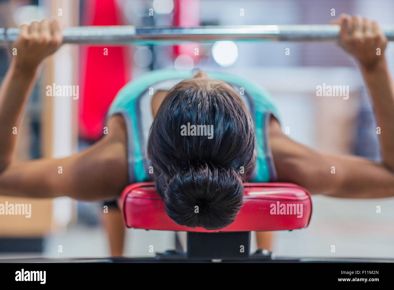 Young woman workout with barbell on the bench in fitness gym Stock Photo