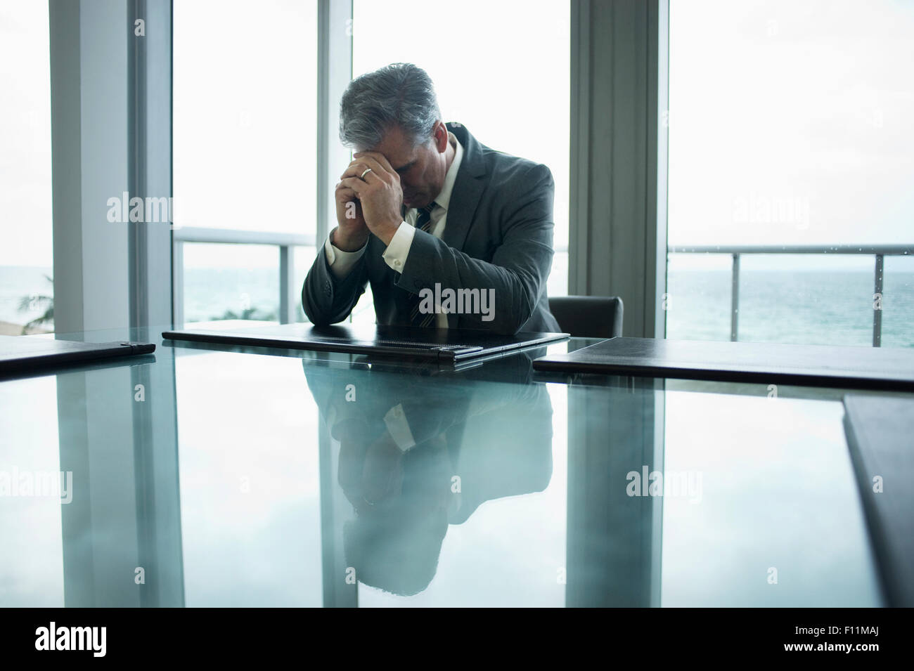 Caucasian businessman holding head in hands at conference table Stock Photo