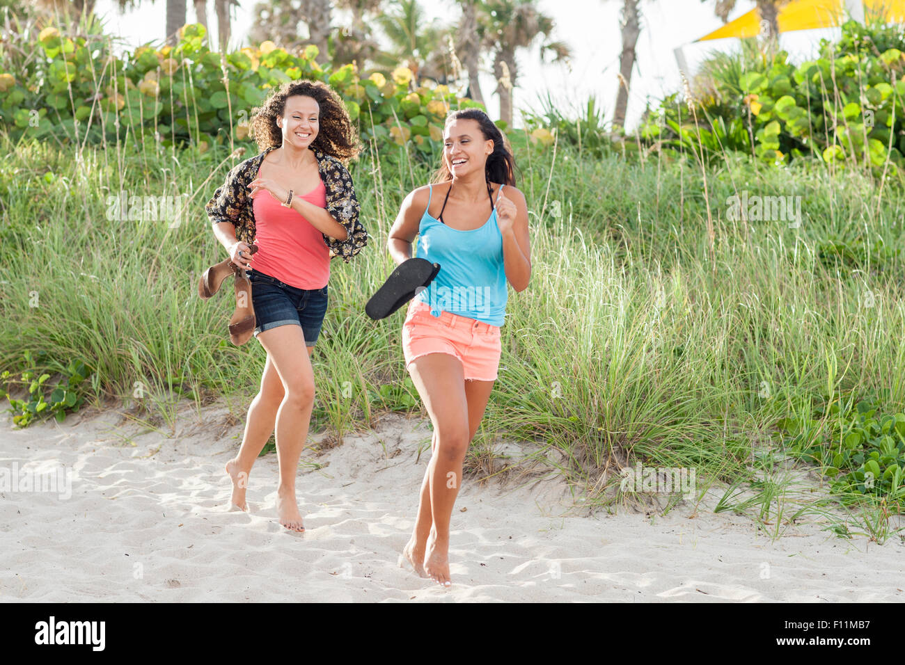 Women carrying shoes running on beach Stock Photo Alamy