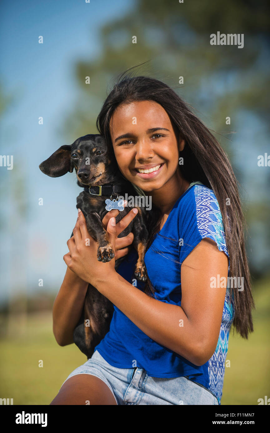 Mixed race girl hugging dog outdoors Stock Photo