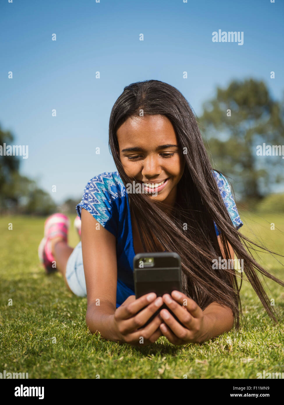 Mixed race girl using cell phone in park Stock Photo