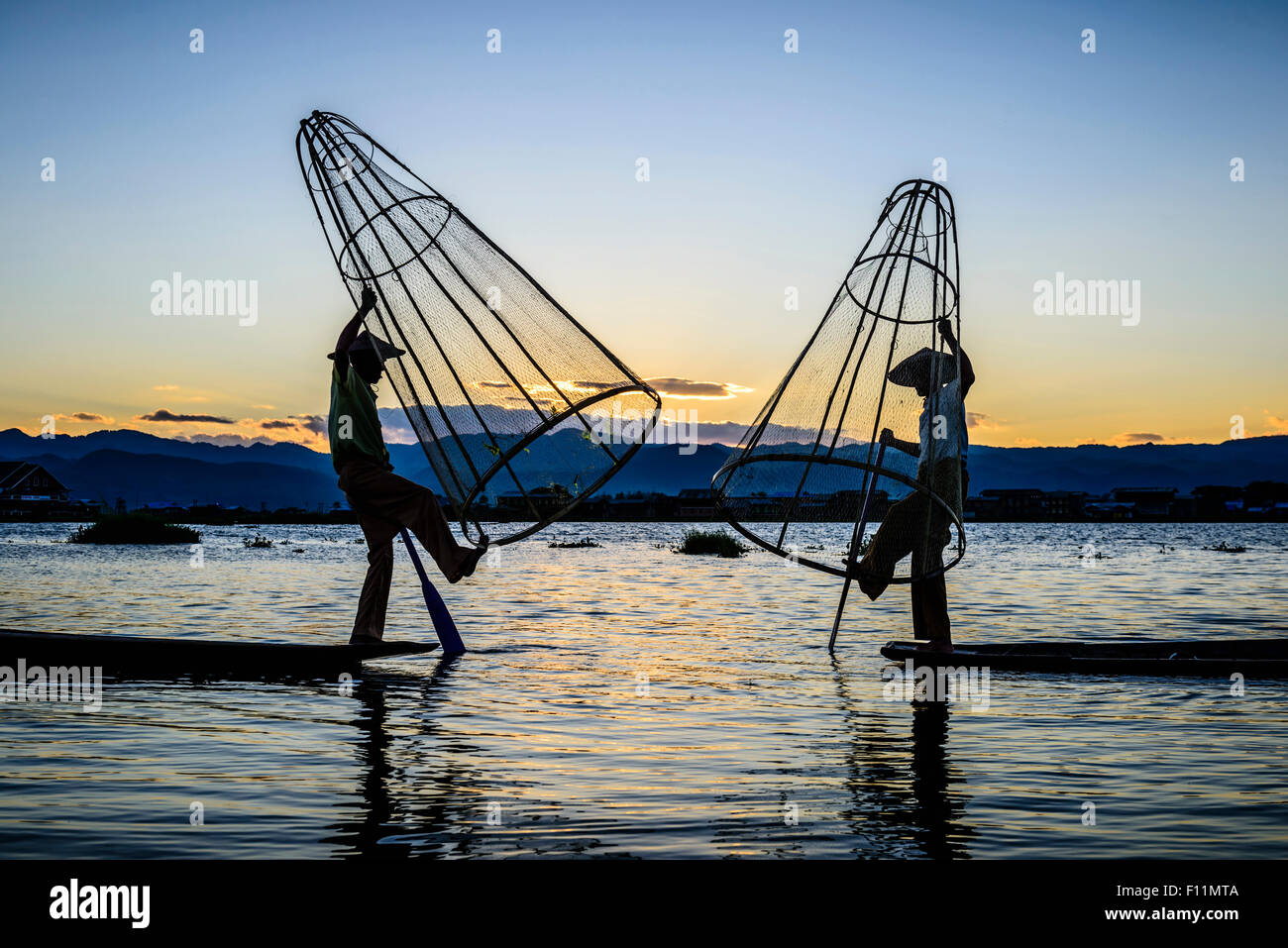 Asian fishermen using fishing nets in canoe on river Stock Photo