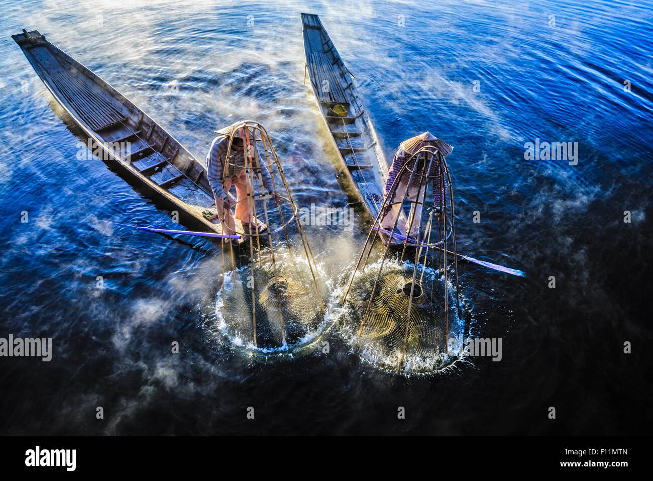 High angle view of Asian fishermen using fishing net in canoes on river Stock Photo