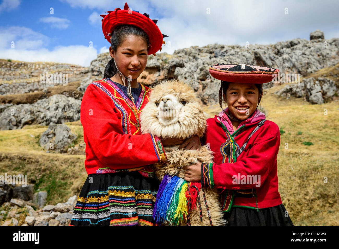 Hispanic sisters smiling with llama in rural landscape Stock Photo