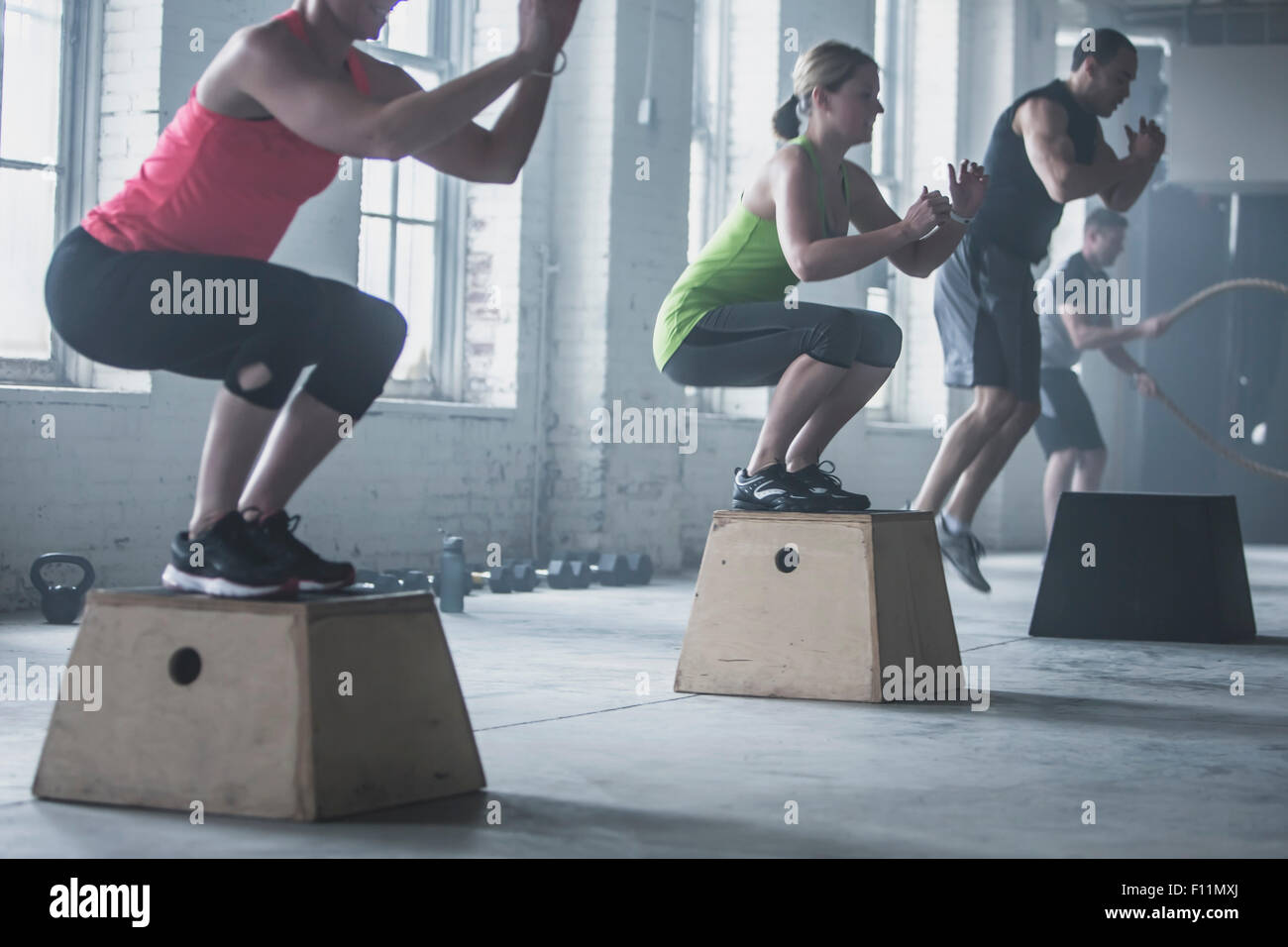 Athletes crouching on platforms in gym Stock Photo