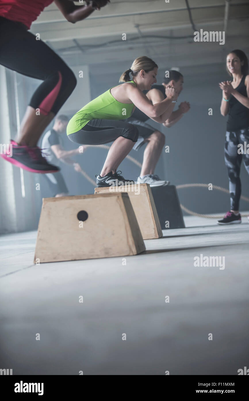 Athletes jumping on platforms in gym Stock Photo