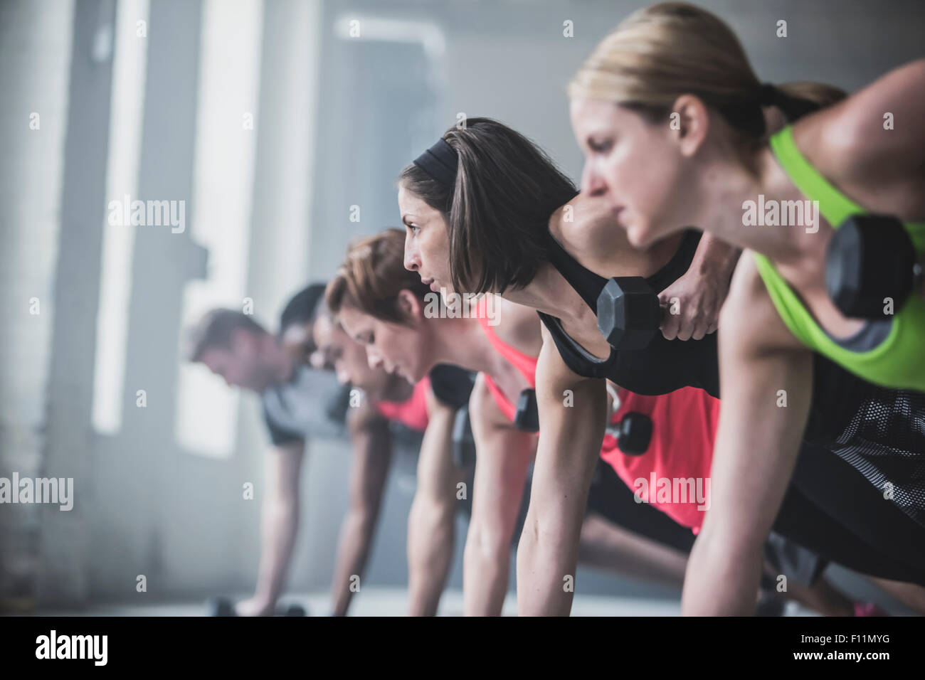 Athletes doing push-ups and lifting weights on floor Stock Photo