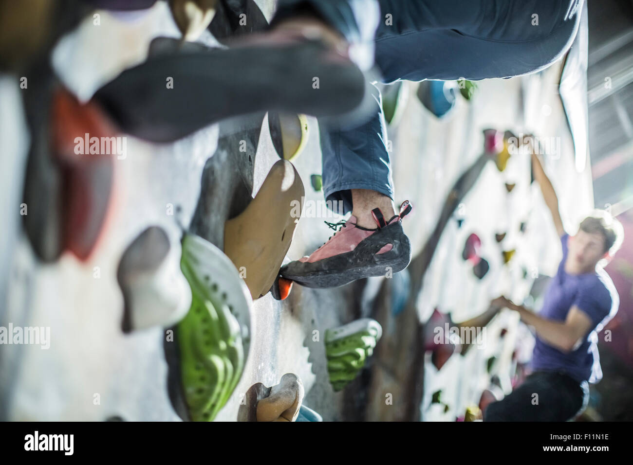 Athletes climbing rock wall in gym Stock Photo