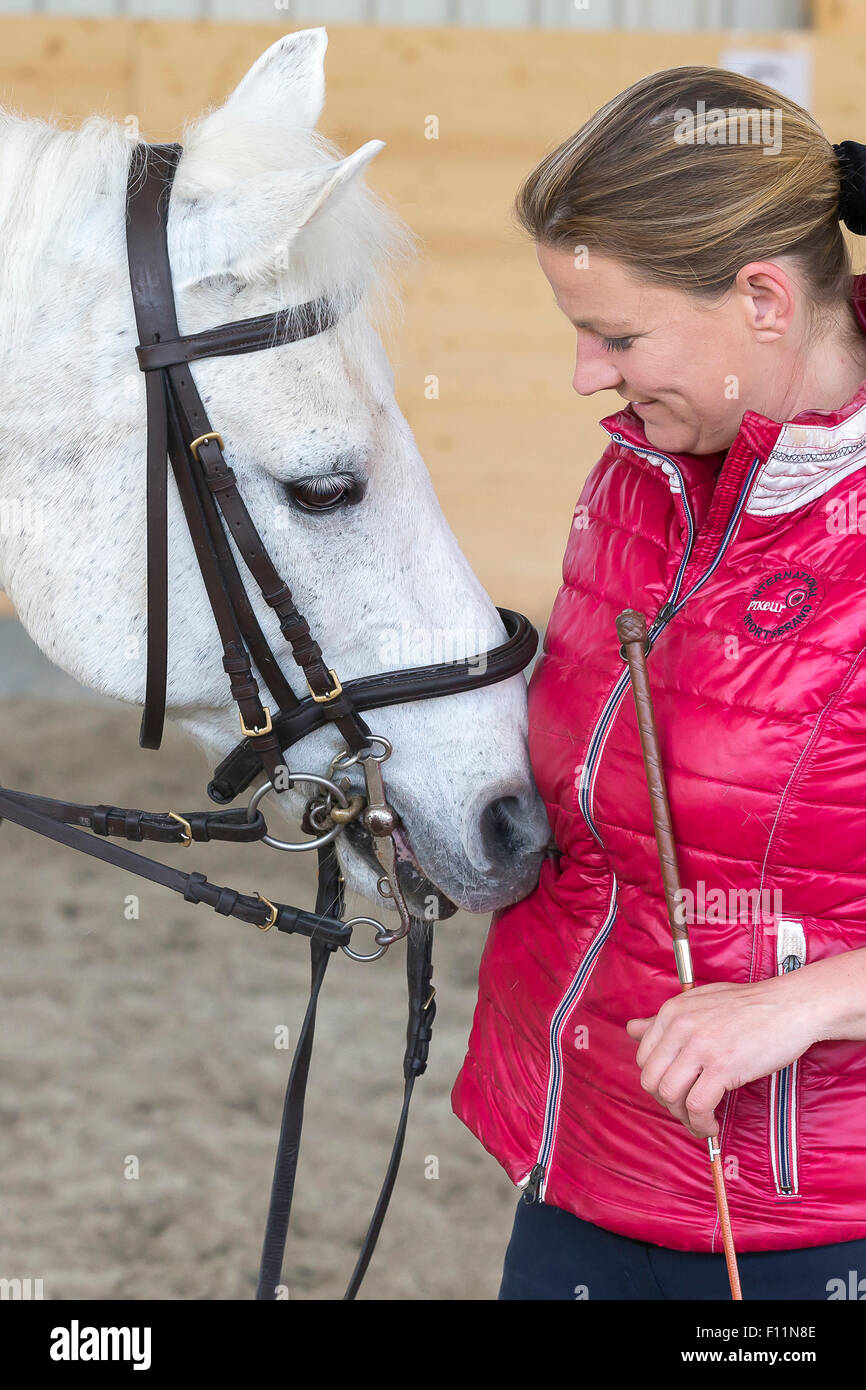German Riding Pony Rider after riding lesson smoothing white pony Stock