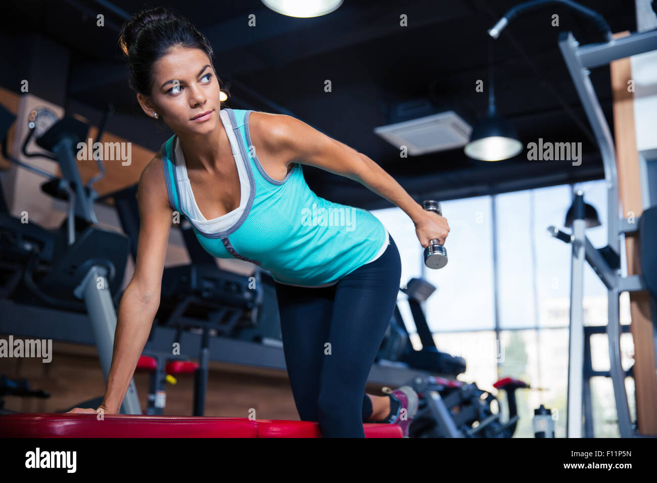 beautiful-woman-workout-with-dumbbell-on-the-bench-in-gym-stock-photo