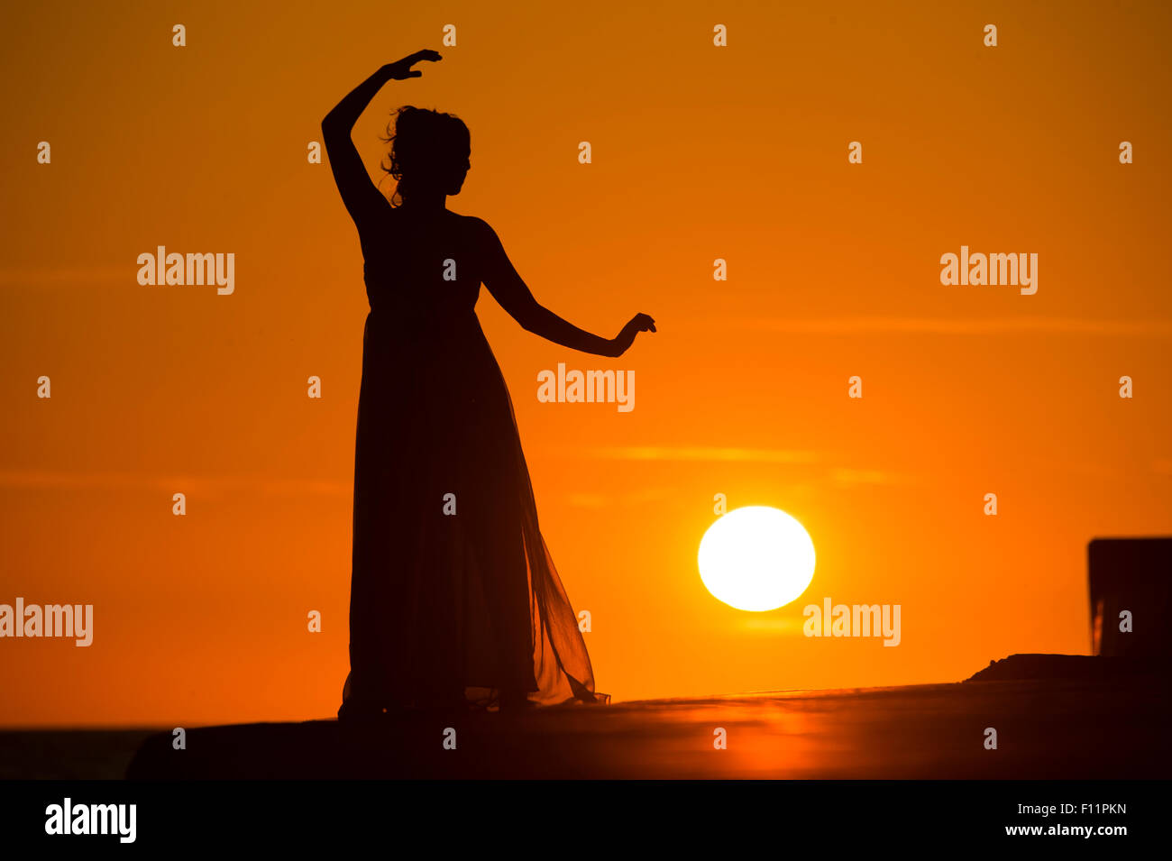 A silhouette of a women girl posing modeling as a 'greek goddess' at sunset Stock Photo