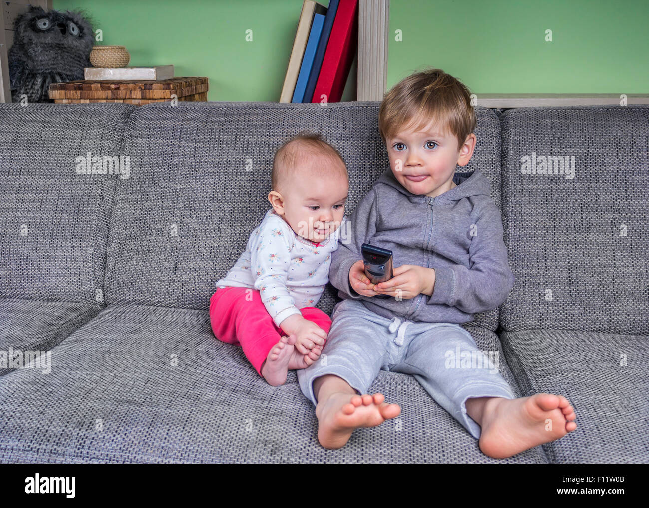 Two Small Children Watching Television On The Couch Stock Photo