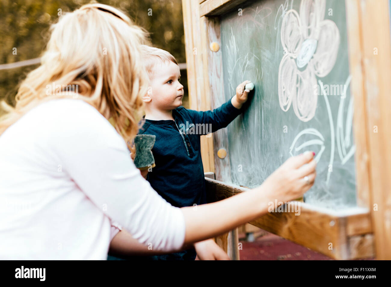Beautiful mother and son drawing on blackboard with chalk Stock Photo