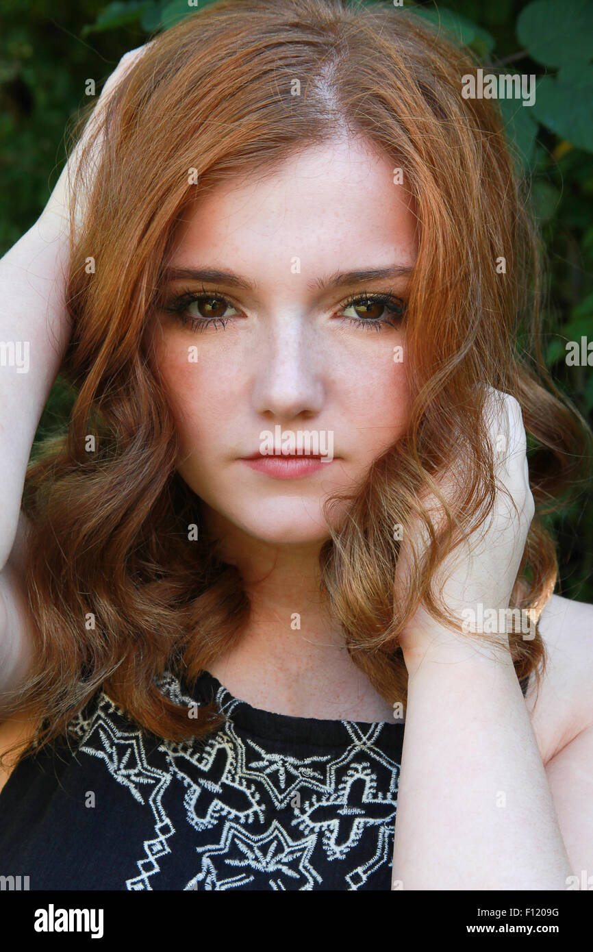 Beautiful young woman with red hair looking straight to camera with beautiful brown eyes. Stock Photo