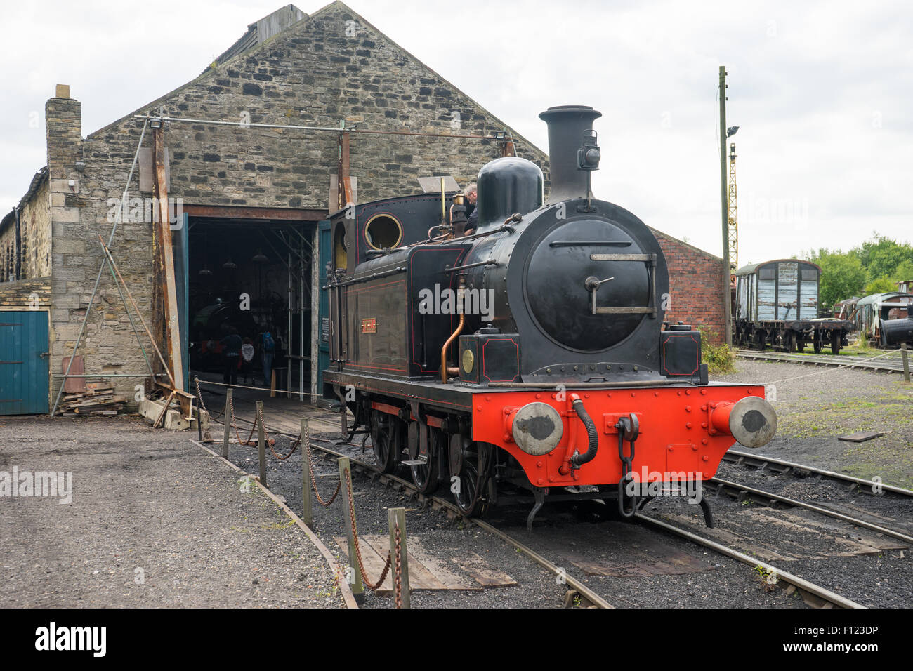 Steam train outside a works shed, at Tanfield Railway, the oldest railway in the world.  A man is working on the train. Stock Photo