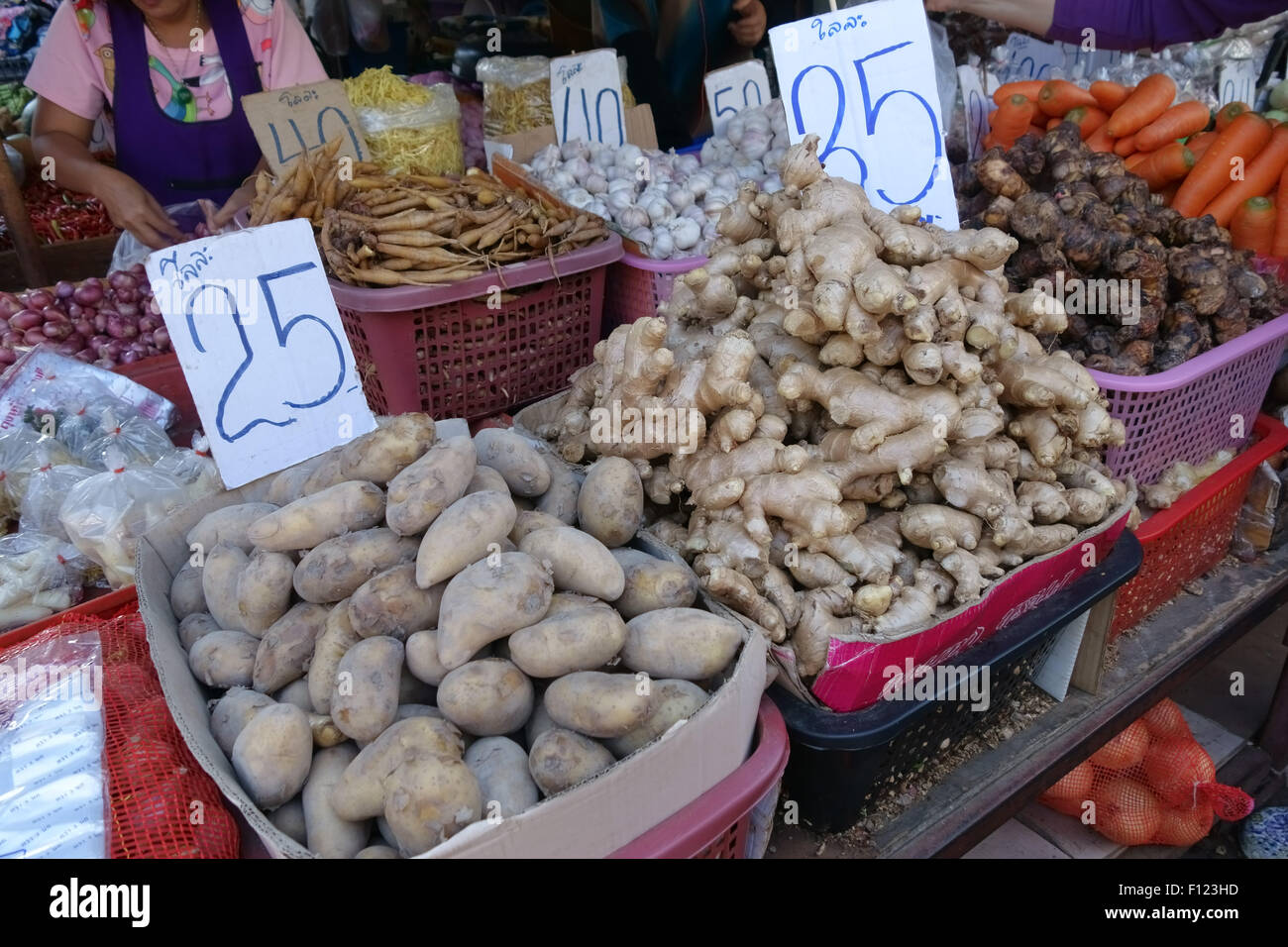Root crops including potato, ginger, garlic, shallots, carrots and other produce on a stall in a Bangkok food market, Thailand Stock Photo