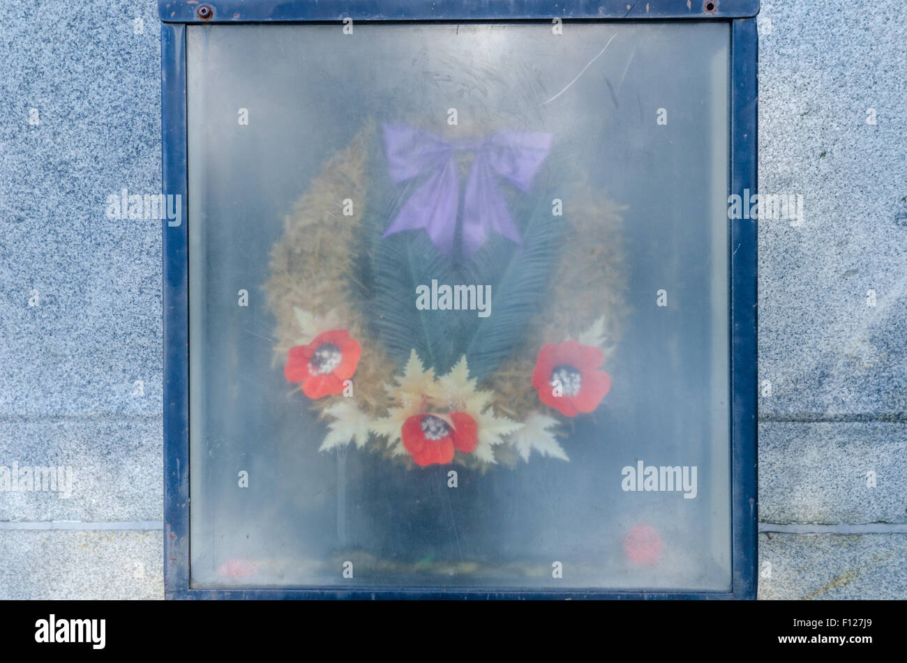 Old commemorative wreaths behind a faded window. Stock Photo