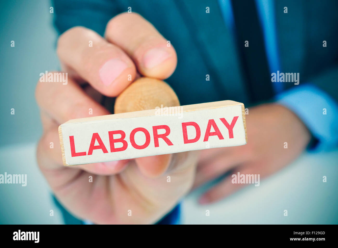 a young caucasian man at his office desk with a rubber stamp with the text labor day Stock Photo