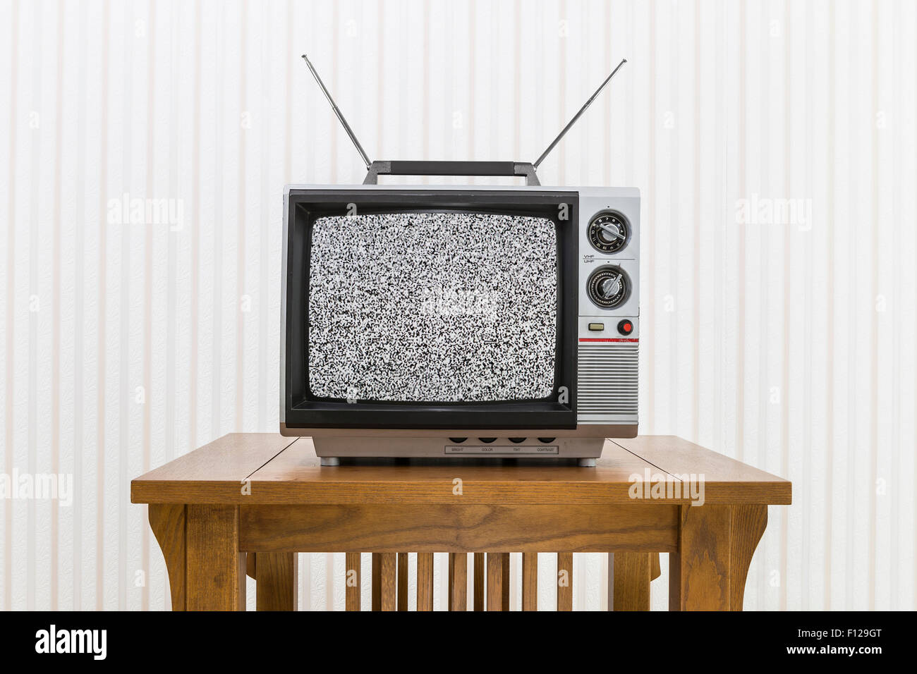 Old portable television with antenna on wood table with static screen. Stock Photo