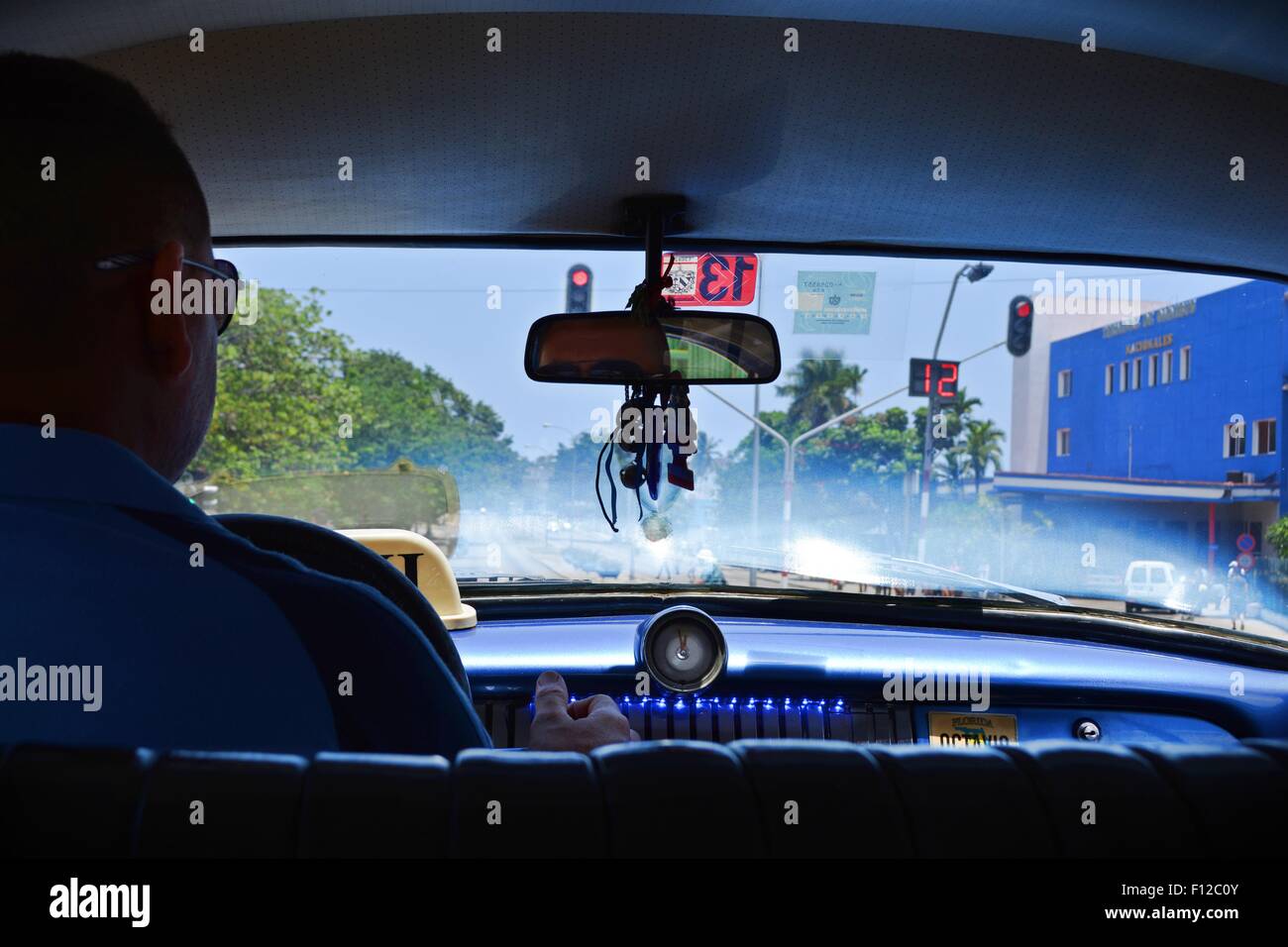 vintage taxi ride - interior shot of driver in shades and illuminated dashboard - on the road in Havana, Cuba Stock Photo