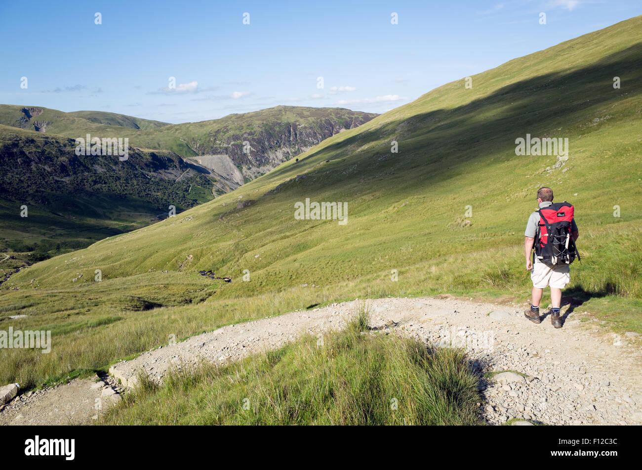 A man with a rucksack descents from the summit of mount Helvellyn, 950 metres high above Lake Ullswater, Lake District, Cumbria, Stock Photo
