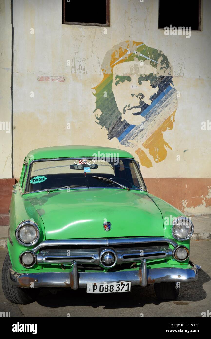 Vintage Green Ford taxi parked beneath Che Guevara mural in the parking lot in Old Havana Cuba Stock Photo