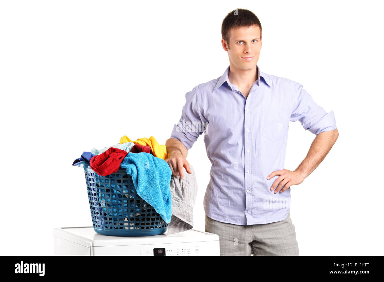 Guy standing by a washing machine with a laundry basket on it isolated on white background Stock Photo