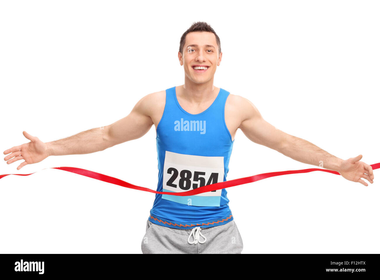 Male runner with a race number on his chest, crossing the finish line
