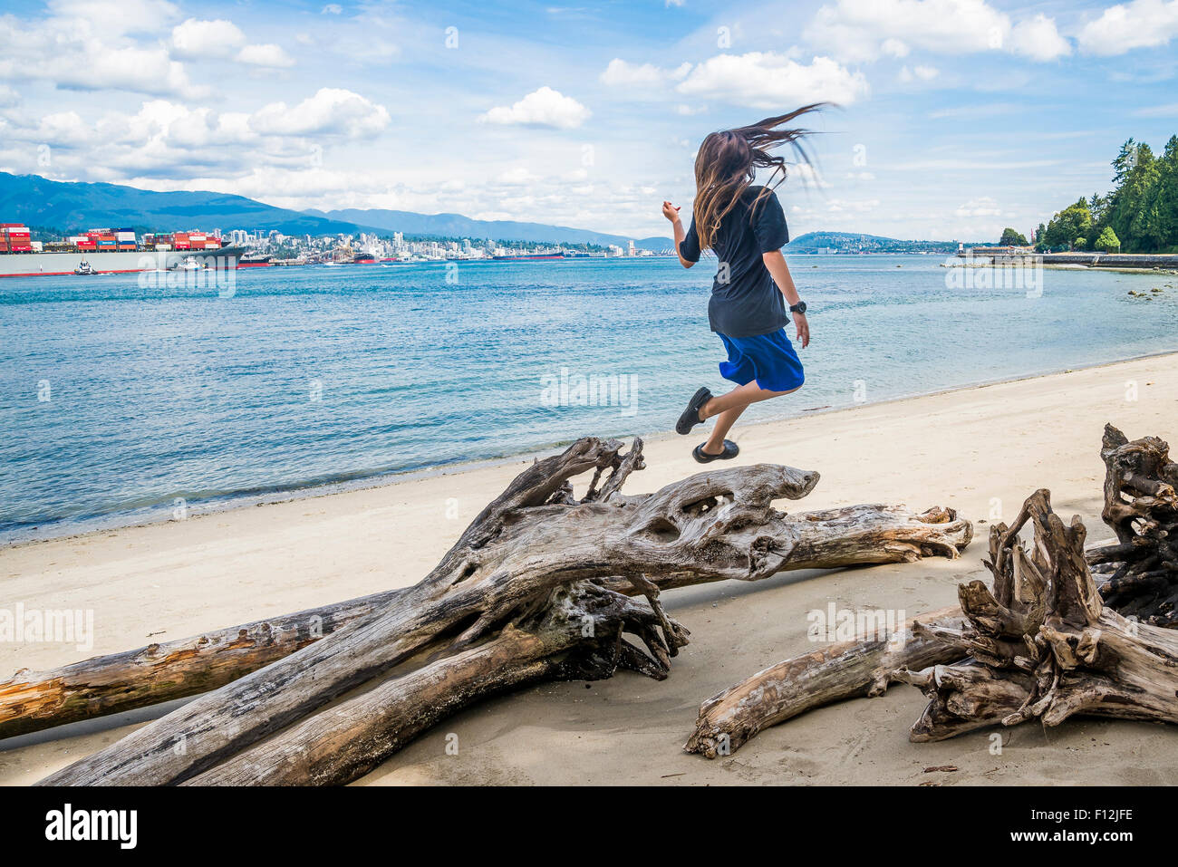 Boy has fun jumping at Beach in Stanley Park, Vancouver, British Columbia, Canada Stock Photo