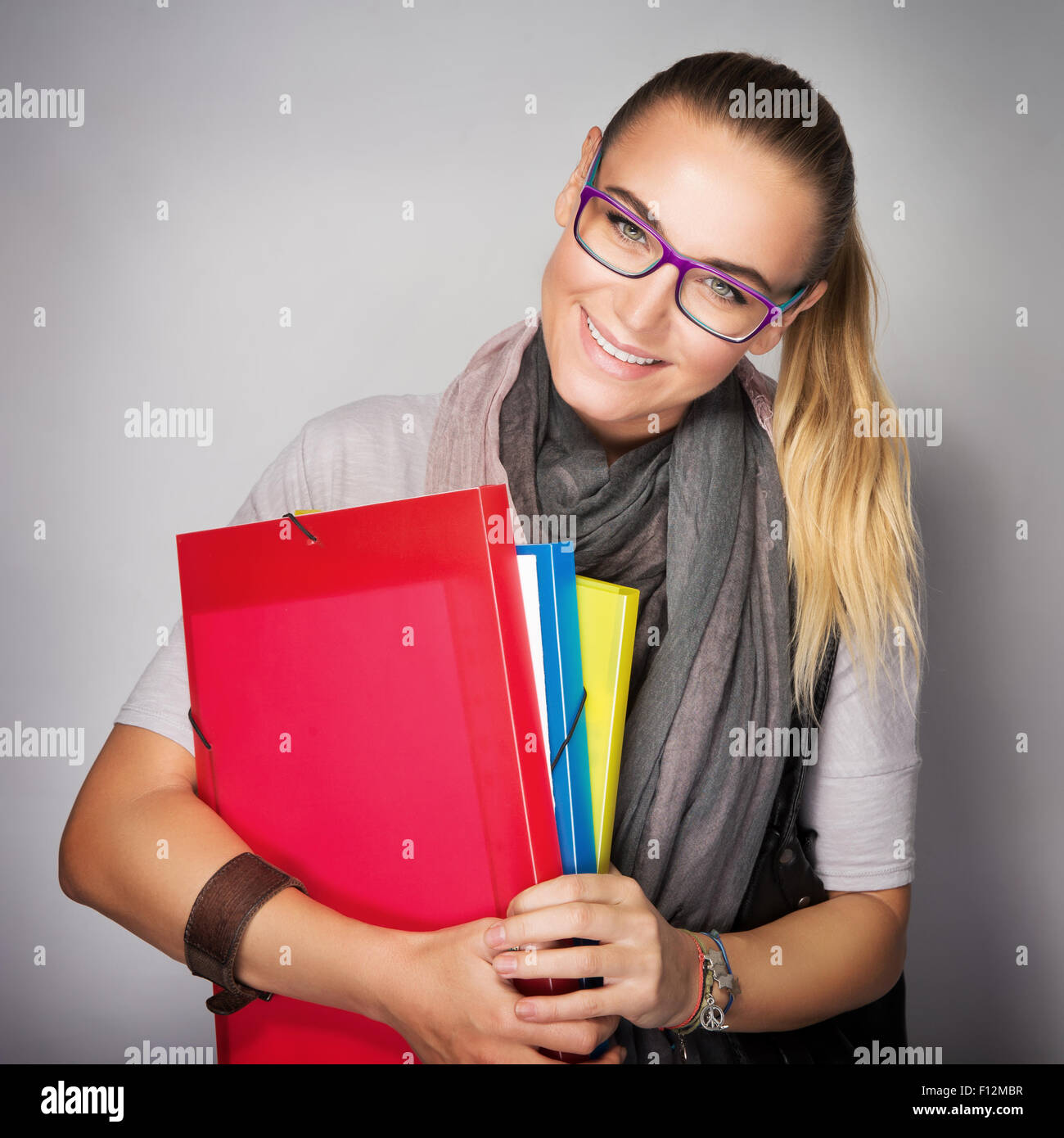 Cute smiling student girl with colorful folders in hands posing in the ...