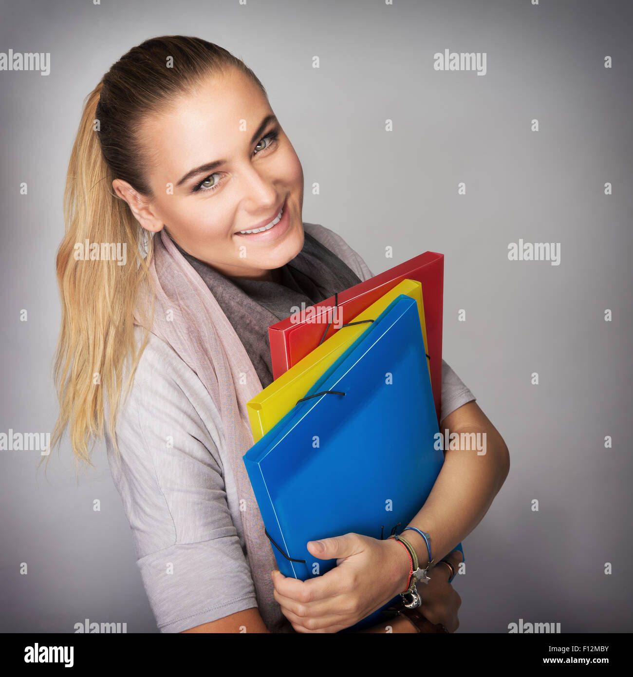Portrait of beautiful happy student girl with colorful folders in hands ...
