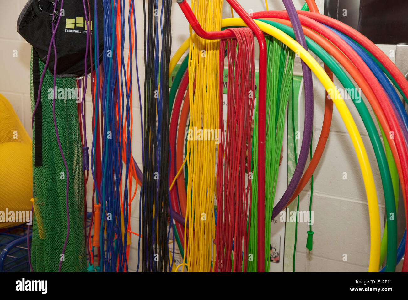 Colorful Hula Hoops and jump ropes hanging on hooks in school gymnasium. St Paul Minnesota MN USA Stock Photo
