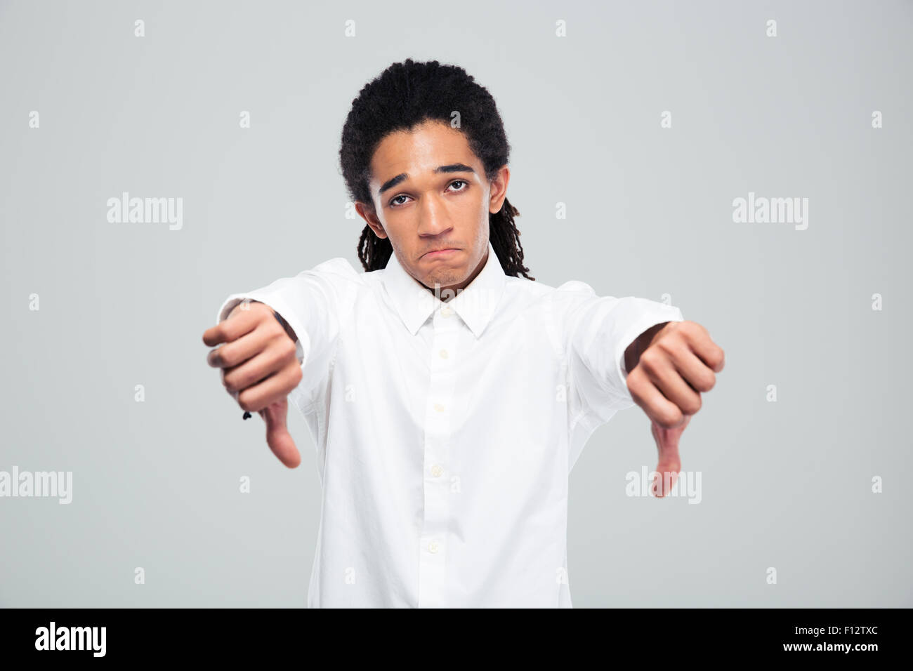 Portrait of a young afro american businessman showing thumbs down over gray background Stock Photo