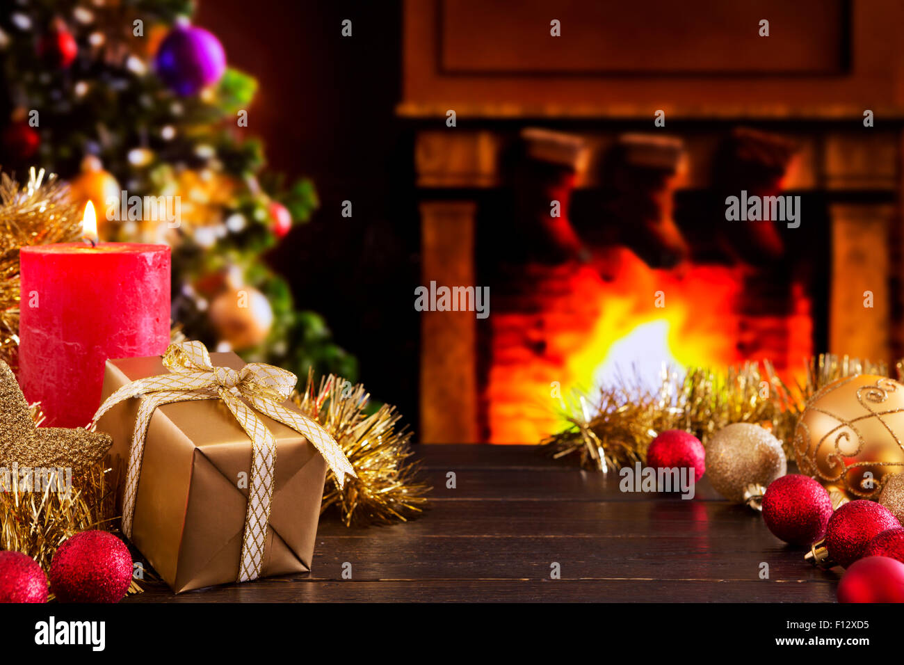 Christmas decorations, a gift and a candle in front of a fireplace. A