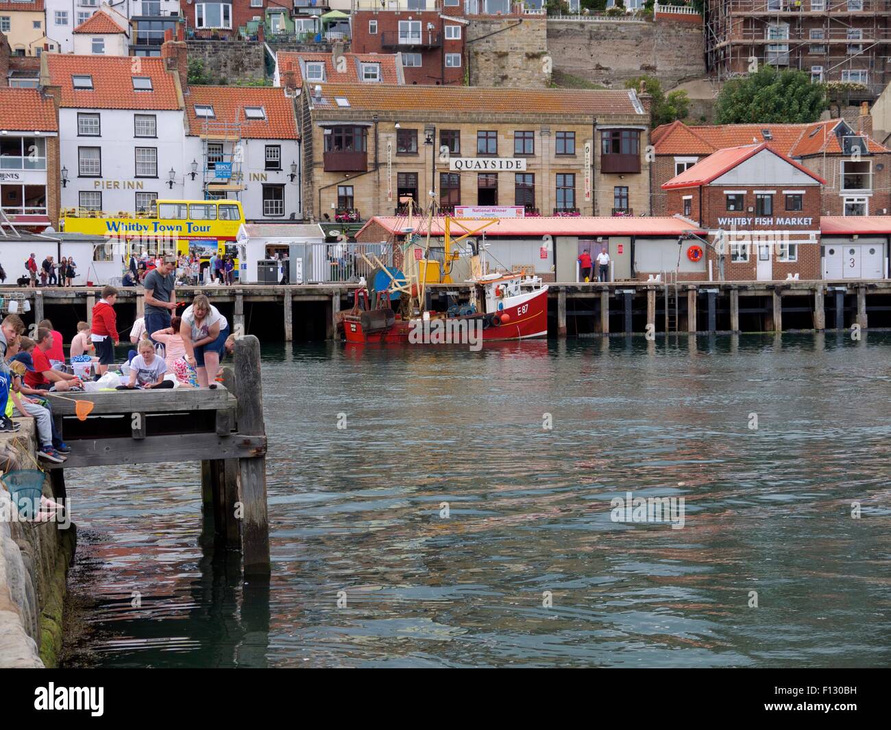 People crab fishing in Whitby with the tour bus passing by in the