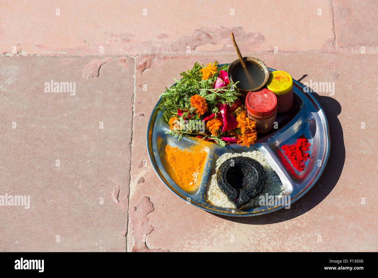 A plate full of colour powder, rice and flowers, used for religious ceremonies at the banks of the river Ganges, Gangotri Stock Photo