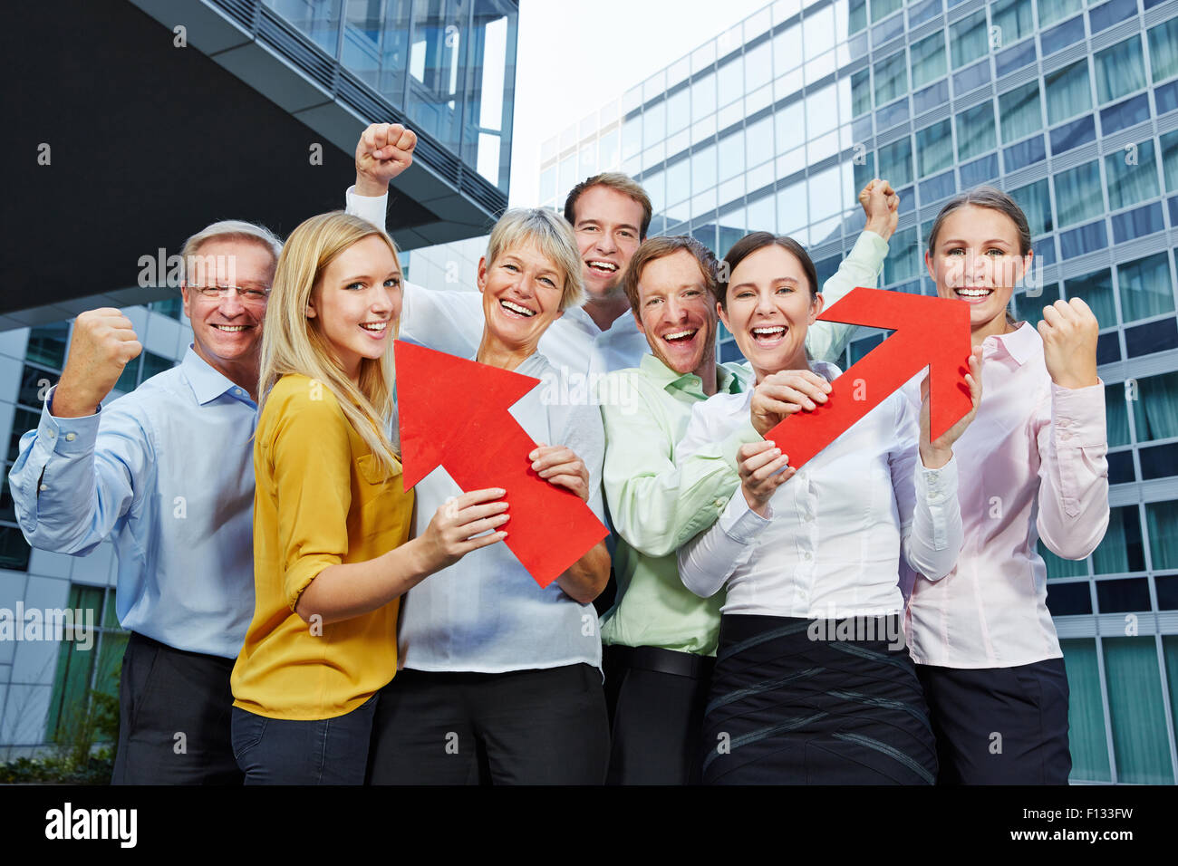 Cheering business people team winning with red arrows pointing up Stock Photo