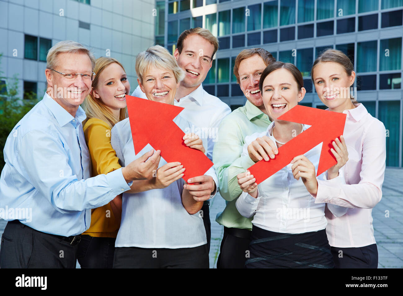 Business team holding big red arrows as symbol for career and success Stock Photo