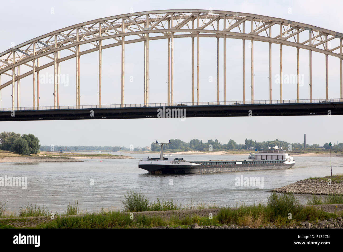 Barge beneath Waalbrug bridge, River Waal, Nijmegen, Gelderland, Netherlands Stock Photo