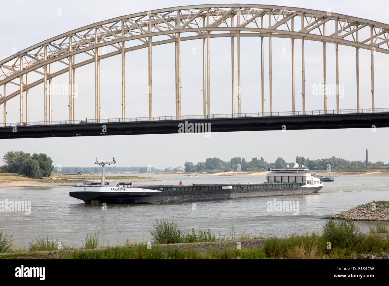 Barge beneath Waalbrug bridge, River Waal, Nijmegen, Gelderland, Netherlands Stock Photo