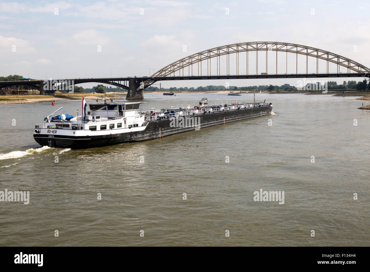 Barge beneath Waalbrug bridge, River Waal, Nijmegen, Gelderland, Netherlands Stock Photo